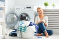 happy woman housewife in the laundry room near the washing machine with dirty clothes