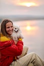 Happy woman hugging spitz dog sitting on peak of mountains, river in the background Royalty Free Stock Photo