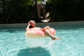 Happy woman and inflatable swim ring in shape of a donut in the pool. Royalty Free Stock Photo