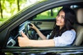 Happy brunette woman inside a car driving in the street and gesturing thumb up