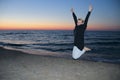 Happy woman jumped on the seashore at sunset Royalty Free Stock Photo