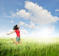 Happy Woman jumping in green grass fields with clouds sky Royalty Free Stock Photo