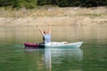 Happy woman in a kayak raising arms celebrating vacation