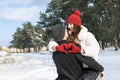 Happy woman keeps hands in heart shape sign sitting on her guy hands. Young loving couple embrace in winter forest Royalty Free Stock Photo