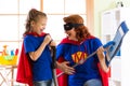 Happy woman and kid prepare for room cleaning. Mother and her child girl playing together. Family in Superhero costumes.