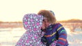 Happy woman kisses her child in a winter park against a sunset background