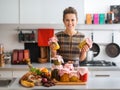 Happy woman in kitchen holding jars of preserved vegetables Royalty Free Stock Photo