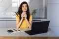 Happy young woman in the kitchen reading he news on her laptop Royalty Free Stock Photo