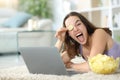 Happy woman with laptop playing with potato chips