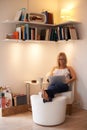 Happy, woman and laptop for relax on chair typing, reading or writing in living room at home. Female person, freelancer