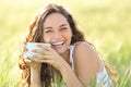 Happy woman laughing looking at you holding coffee cup in nature Royalty Free Stock Photo