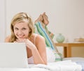 Happy woman laying on bed in bedroom using laptop Royalty Free Stock Photo