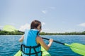 Happy woman with lifejacket kayaking in tropical island ocean on vacation. Royalty Free Stock Photo