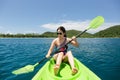 Happy woman with lifejacket kayaking in tropical island ocean on vacation. Royalty Free Stock Photo