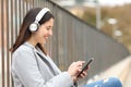Happy woman listening to music sitting in the street Royalty Free Stock Photo