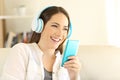 Happy woman listening to music using blue phone