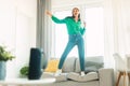 Happy woman listening to song via modern music speaker, having fun and dancing on sofa at home, selective focus Royalty Free Stock Photo