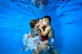 Happy woman, little girl and boy are swimming and playing underwater in the pool. Children kiss their mother on the Royalty Free Stock Photo