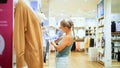 Happy woman looking at clothing in shopping center clothing store mall. Female shopper enjoying purchase in branded