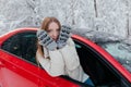 Happy woman looks out the car window, covering her face with her hands. Winter forest Royalty Free Stock Photo