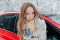 Happy woman looks out the car window, holds a cookie in the form of a man in her hands. Winter forest Royalty Free Stock Photo