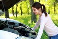 Happy woman looks under hood car