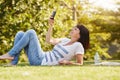 Happy woman lying in grass taking selfie with smart phone Royalty Free Stock Photo