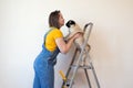 Happy woman makes repairs in her apartment. Funny female with a roller on ladder with copy space. Independent single Royalty Free Stock Photo