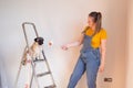 Happy woman makes repairs in her apartment. Funny female with a roller on ladder with copy space. Independent single Royalty Free Stock Photo