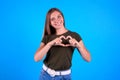 Happy woman making heart with her hands on blue background Royalty Free Stock Photo