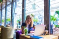 Cheerful female blogger having pleasant conversation via cell telephone during breakfast in cafe Royalty Free Stock Photo