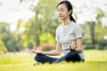 Happy woman meditating on the grass at park,asian child girl practicing yoga meditation in nature outdoor,enjoy breathing fresh Royalty Free Stock Photo