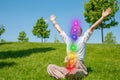 Happy woman is meditating in the lotus pose with glowing seven chakras on grass. Woman is practicing yoga on the park Royalty Free Stock Photo