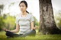 Happy woman meditating in yoga pose or lotus position on the green grass under the tree at park,asian child girl practicing yoga Royalty Free Stock Photo