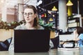 Happy woman millennial using laptop while sitting at cafe.Young businesswoman sitting in coffee shop,working on computer