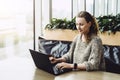 Happy woman millennial using laptop while sitting at cafe.Young businesswoman sitting in coffee shop,working on computer