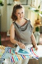 Happy woman in modern living room in sunny day ironing on board Royalty Free Stock Photo