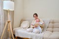 Happy woman mother with infant baby watching in digital tablet while sitting on home sofa in living room Royalty Free Stock Photo