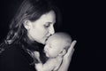 Happy woman mother kissing a newborn baby boy in her arms, black studio background. Mom with a child in her hands Royalty Free Stock Photo