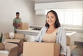 Happy woman, moving and carry box in new house for property, investment and real estate in living room. Female homeowner Royalty Free Stock Photo