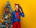 Happy woman near Christmas tree using a mobile phone Royalty Free Stock Photo