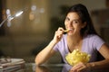 Happy woman in the night eating potato chips