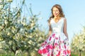 Happy Woman in an orchard at springtime. Enjoying sunny warm day. Retro style dress. Blooming blossom cherry trees Royalty Free Stock Photo