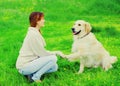 Happy woman owner is training her Golden Retriever dog on grass and giving paw to hand Royalty Free Stock Photo