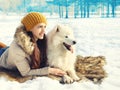 Happy woman owner with white Samoyed dog lying together on snow Royalty Free Stock Photo