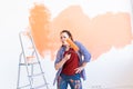 Dancing funny smiling woman painting interior wall of new house. Redecoration, renovation, apartment repair and Royalty Free Stock Photo