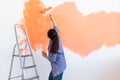 Dancing funny woman painting interior wall of new house. Redecoration, renovation, apartment repair and refreshment Royalty Free Stock Photo