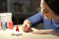 Happy woman painting nails at night at home