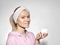 Happy woman with perfect skin applying cream on cleansed face. Concept of skincare, beauty industry and facial treatment
