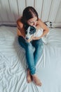 Happy woman petting a Labrador puppy in bed. The Labrador puppy is in her arms